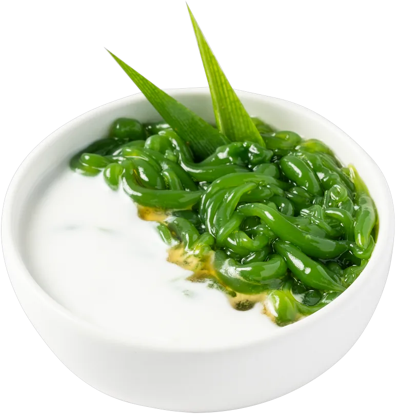 Bowl of green pandan jelly in coconut cream with pandan leaves